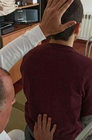 Persona realizando una terapia de sanación energética para recuperar la salud del paciente. Tocando su cabeza y espalda