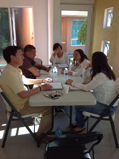 Grupo de personas sentadas en una mesa estudiando la teoría del curso de sanación presencial en España